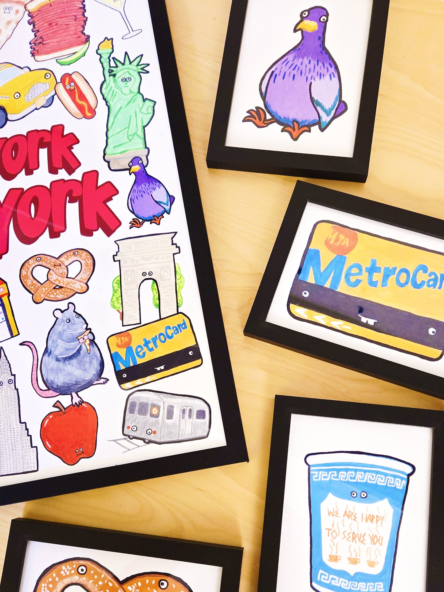 Framed illustrations by The Carrot Press of New York-themed items on a wooden surface