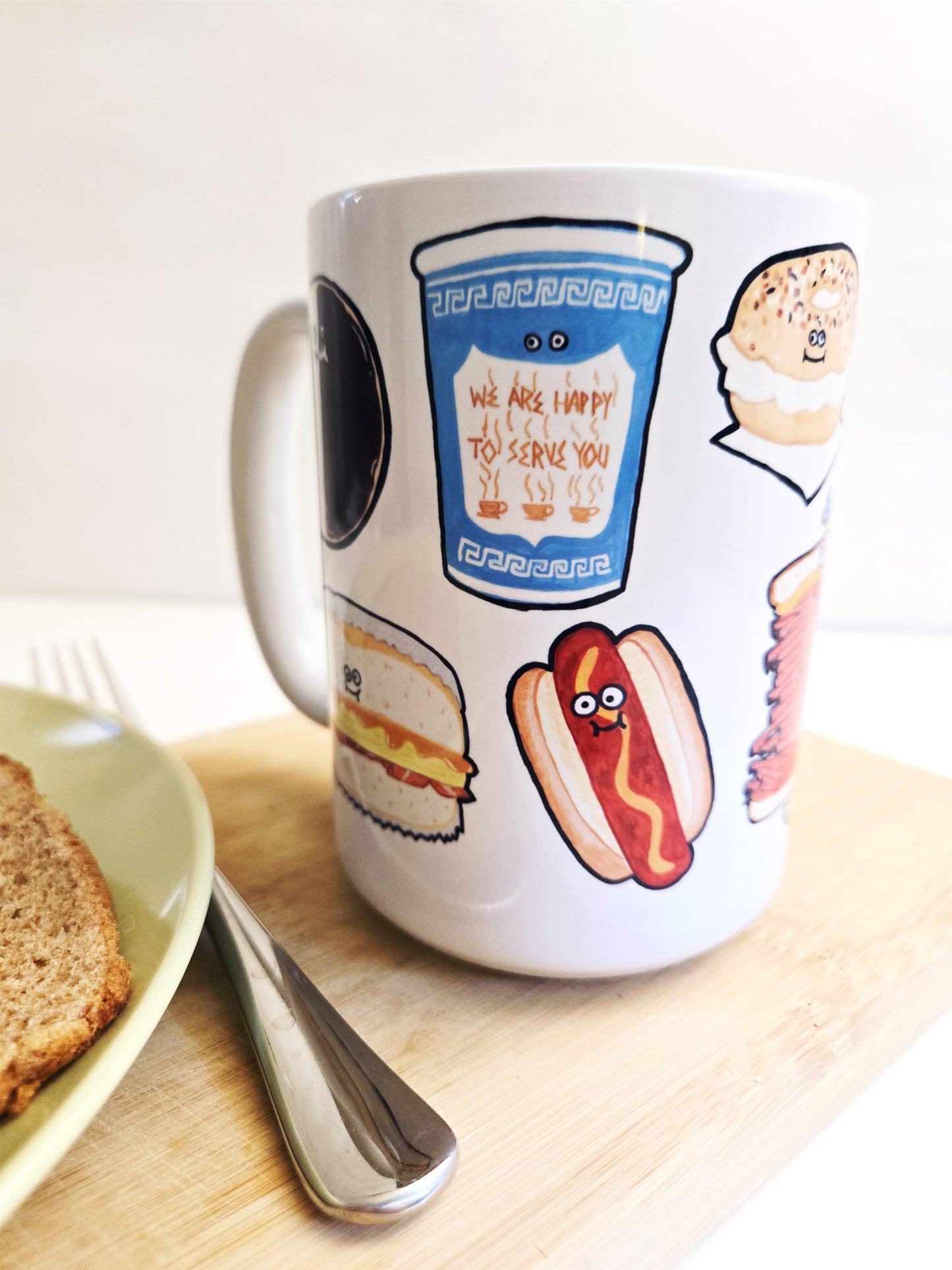 White mug with NYC food-themed illustrations on a wooden surface